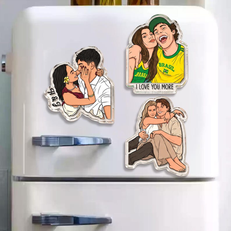 May include: Three custom acrylic magnets featuring illustrated couples. One shows a couple with the text H & G, another shows a couple in Brazil shirts with the text I LOVE YOU MORE, and the third shows a couple embracing while sitting together.
