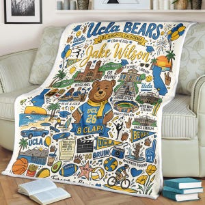 Puede incluir: Una manta blanca de UCLA Bears con un dise&ntilde;o colorido con el texto "UCLA BEARS" y "Jake Wilson". La manta incluye ilustraciones de lugares emblem&aacute;ticos, una mascota de oso y el texto "Class of 2026".