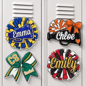 May include: Four decorative acrylic magnets featuring cheerleading themes. One shows a blue and yellow megaphone with the name Emma, another a black and orange megaphone with the name Chloe, a green bow with CS and Rachel, and a red, black, and white pom-pom with Emily.