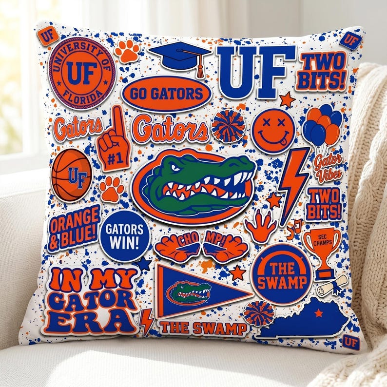 Puede incluir: Un coj&iacute;n decorativo con un collage de gr&aacute;ficos naranjas, azules y blancos. El dise&ntilde;o incluye el texto "UF", "Gators", "Orange & Blue" y "The Swamp", junto con un cocodrilo de dibujos animados, huellas de patas y un gorro de graduaci&oacute;n. El coj&iacute;n est&aacute; sobre una superficie blanca.