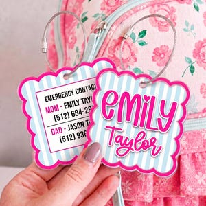 May include: Two square scalloped luggage tags with light blue and white vertical stripes and bright pink borders. One tag displays the name Emily Taylor in pink script. The other tag lists emergency contact information for Mom and Dad.