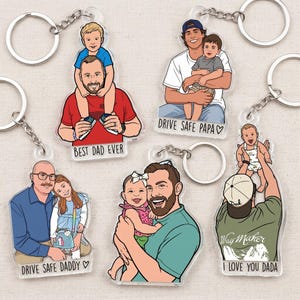 May include: Acrylic keychains featuring cartoon illustrations of fathers with their children. Each keychain has a silver chain and ring. Text on the keychains includes "Best Dad Ever," "Drive Safe Papa," "Drive Safe Daddy," and "I Love You Dada."