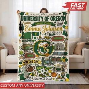 Puede incluir: Una manta crema de la Universidad de Oreg&oacute;n con un dise&ntilde;o verde y amarillo. Presenta el texto "University of Oregon" y "Emma Johnson", junto con ilustraciones de la mascota de los Oregon Ducks y monumentos del campus.