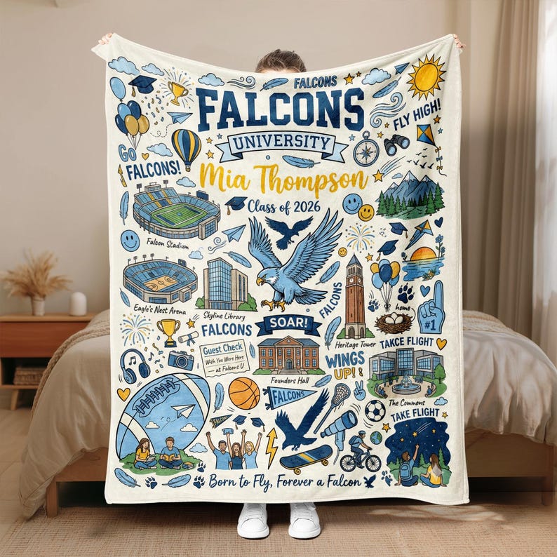 Puede incluir: Manta color crema con un dise&ntilde;o universitario azul y amarillo. Presenta el texto "Falcons University" y "Mia Thompson Class of 2026". Incluye ilustraciones de un estadio, un &aacute;guila y otros s&iacute;mbolos universitarios.
