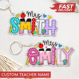 May include: Two personalized teacher name keychains. One says "Mrs. Smith" and the other says "Miss Emily". Each keychain features colorful letters, pencils, apples, and a globe. The keychains are attached to a gold-colored chain and ring.