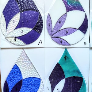 May include: A collection of teardrop-shaped stained glass pieces in various colors, including purple, blue, white, and teal. Each piece is divided into sections with numbered labels, showcasing different textures and patterns. The letter "A", "B", "E", and "F" are visible on the bottom right of each piece.