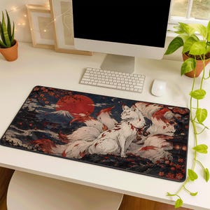 May include: A rectangular desk mat featuring a multi-tailed white fox with red markings, set against a dark landscape with a large red sun, a mountain silhouette, and cherry blossom branches. The design includes flowing fur details.