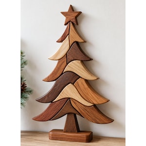 Pode incluir: Uma escultura decorativa de árvore de Natal feita de vários tons de madeira natural. A árvore apresenta segmentos de madeira curvos e empilhados em tons de castanho claro, médio e escuro, rematados com uma estrela de cinco pontas e uma base.