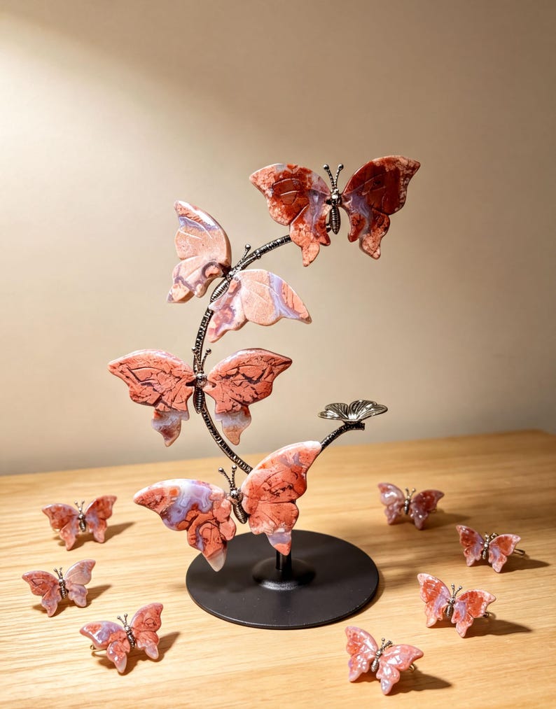 a decorative sculpture of butterflies, with a total of 14 butterflies displayed on a wooden surface. The butterflies are painted in shades of red and orange and are arranged in a circular pattern around a black base.