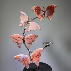 A hand is holding a decorative sculpture of butterflies on a black base.