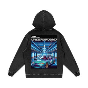 May include: Black hooded sweatshirt with a graphic on the back featuring a teal and purple sports car. The graphic includes the text "JDM Car Meet Underground" in white and the car has gold rims. The sweatshirt has a vintage wash.