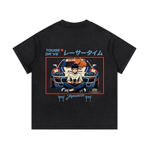 May include: Black t-shirt featuring a graphic of a person sitting in front of a race car with a cat on top. The text on the shirt includes "TOUGE DR'VE", Japanese characters, and "Japanese".
