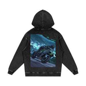 May include: Black washed hoodie featuring a graphic of a motorcycle racing down a road at night. The motorcycle is black and green, with the rider in black gear. The background shows a city with bright lights and mountains.