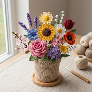 May include: A handmade crochet flower arrangement in a beige pot. The bouquet features a variety of colourful flowers including sunflowers, roses, daisies, and lavender. The arrangement sits on a wooden coaster, with yarn and a crochet hook visible.