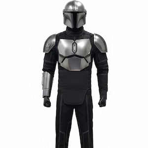 May include: A full-body costume featuring a silver metallic helmet, chest plate, shoulder pauldrons, and a forearm gauntlet. The suit includes a black long-sleeved top with quilted detailing, matching black trousers with visible stitching, and black gloves.