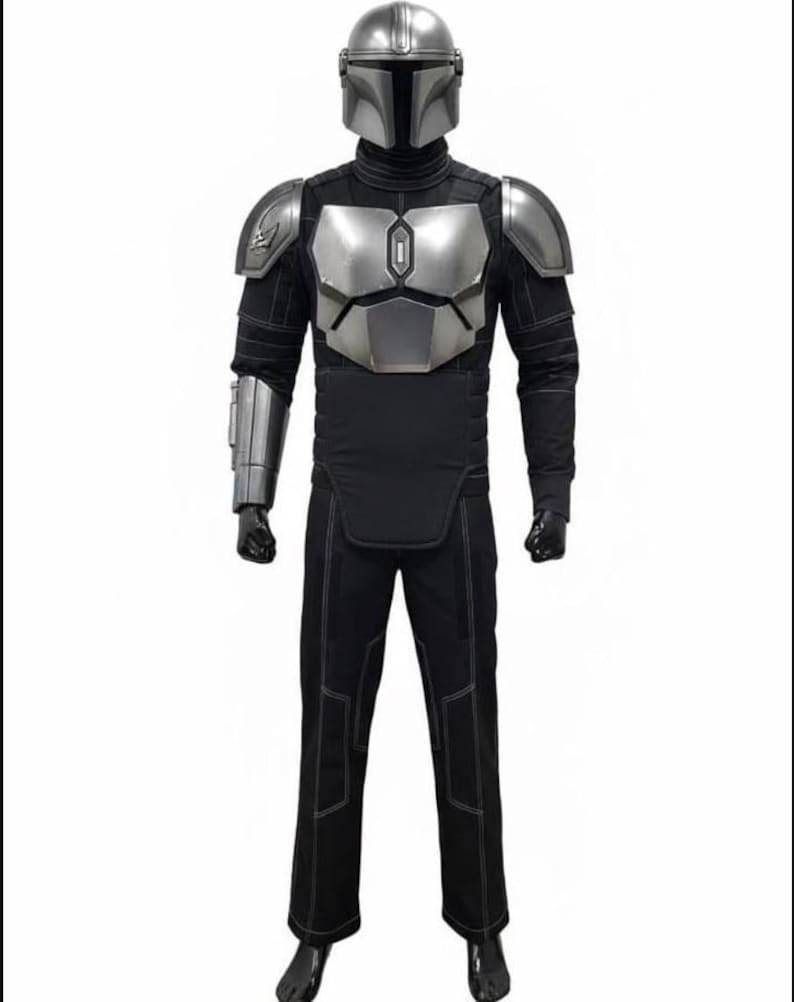 May include: A full-body costume featuring a silver metallic helmet, chest plate, shoulder pauldrons, and a forearm gauntlet. The suit includes a black long-sleeved top with quilted detailing, matching black trousers with visible stitching, and black gloves.