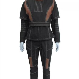 May include: A black two-piece outfit consisting of a short-sleeved top and matching trousers. The top features a high collar, brown shoulder panels, and white topstitching. The trousers have brown knee panels and white topstitching throughout the set.