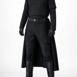 May include: A black outfit consisting of a short-sleeved top with vertical stitching, long sleeves, and matching trousers featuring ribbed knee panels, side cargo pockets, and a long back panel. The ensemble includes black gloves and tall boots.