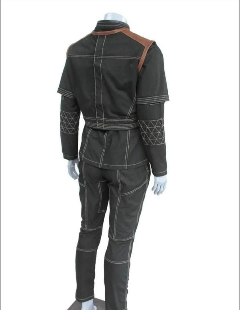 May include: A black two-piece outfit consisting of a jacket and trousers with prominent white contrast stitching. The jacket features brown shoulder panels and a geometric triangular pattern on the sleeves. The trousers have a matching seam design.