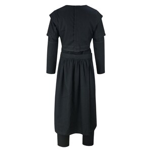 May include: A black long-sleeved garment featuring a structured bodice with layered shoulder detailing and a high neckline. The piece includes a pleated skirt section that falls to a mid-calf length, paired with matching black trousers underneath.