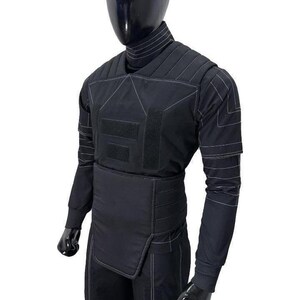May include: A black long-sleeved tactical shirt featuring a high turtleneck collar, padded chest and shoulder panels, and a wide integrated waist belt. The garment is accented with white contrast stitching throughout and rectangular hook-and-loop patches.