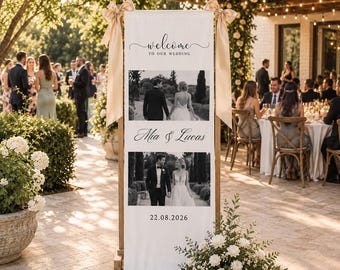 Könnte beinhalten: Ein vertikales, weißes Hochzeits-Willkommensschild auf einem Holzständer mit zwei Schwarz-Weiß-Fotos eines Paares, dem Text "welcome TO OUR WEDDING", den Namen "Mia & Lucas" und dem Datum "22.08.2026", verziert mit zwei großen beigen Satinschleifen.