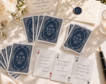 Könnte beinhalten: Ein Set personalisierter Spielkarten mit marineblauer Rückseite, weißem Blumenfiligran und dem Text S & N September 19, 2026. Die Karten haben weiße Vorderseiten mit handschriftlichen Nachrichten für das Brautpaar sowie einen passenden Umschlag.