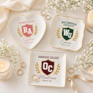 May include: Three white ceramic trinket dishes with gold-painted rims. One heart-shaped dish features a pink shield with RA, one square dish features a green shield with WU, and one square dish features a maroon shield with OC. Each includes text.