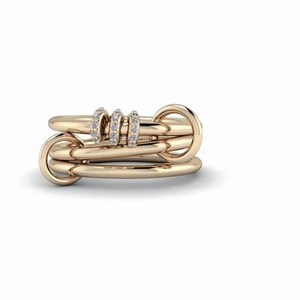 May include: A multi-band ring crafted from polished rose gold, featuring three interconnected smooth bands and three smaller, thinner bands adorned with small, clear, round-cut white diamonds set along their outer surfaces.