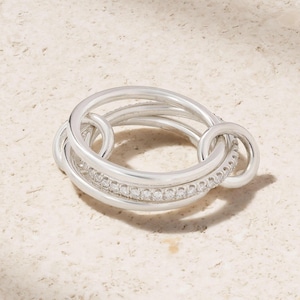 May include: A white ceramic mug with a black handle and the text "But First, Coffee" in a black, handwritten-style font. The mug is on a white surface.