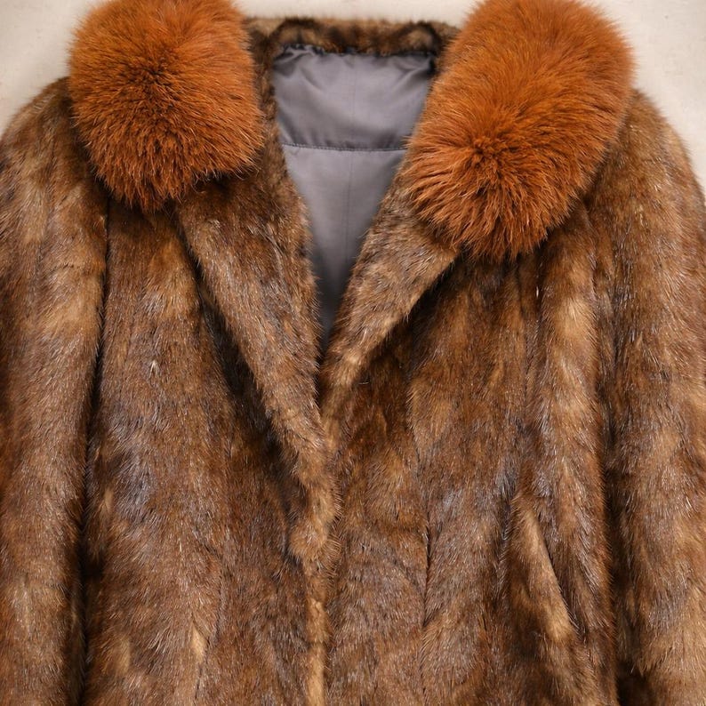 May include: A brown fur coat with a fox fur collar. The coat has a classic design with a notched collar and a long, flowing silhouette. The fur appears soft and luxurious, with varying shades of brown.