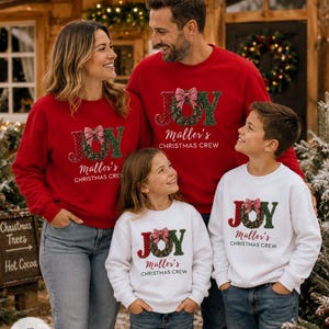 May include: Matching red and white crewneck sweatshirts featuring the text JOY with a wreath replacing the letter O, a red and white checkered bow, and the custom text M&uuml;ller's CHRISTMAS CREW printed in a dark red font on the front of each garment.