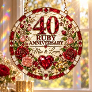 May include: A circular stained glass suncatcher featuring the text 40th RUBY ANNIVERSARY, Mia & Lucas, and 1986-2026. The design includes red roses, pink rosebuds, a large red heart, and two gold wedding rings, all framed by a red and white border.