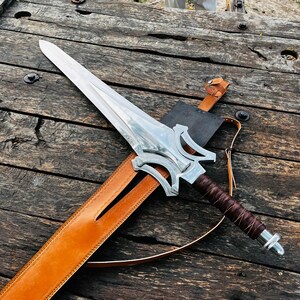 Close up of the handle end cap of the fantasy sword knife showing polished metal finish and solid construction. The design complements the leather wrapped handle and adds to the overall premium feel. This handmade piece is perfect for display collections or as a special gift item.