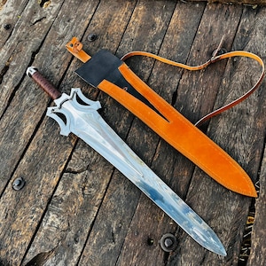 Long blade handmade fantasy knife shown in full product display with sheath placed alongside, emphasizing its impressive length and balanced proportions. The blade features a smooth polished finish while the guard has a bold, artistic shape. Ideal for collectors looking for a unique display piece or as a meaningful gift option for husband or loved ones.