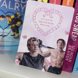 May include: A rectangular card featuring a pink heart-shaped border with a bow and the text 'just a girl who apparently does love blonde mmcs...'. Below, two shirtless men with blonde and brown hair are depicted, with small pink hearts scattered around.