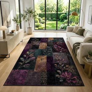 Op de afbeelding: Een rechthoekig vloerkleed met een patchworkontwerp van dieppaarse, donkergroene en bronsgouden blokken. Het kleed is versierd met gedetailleerde botanische illustraties van bladeren en bloemen, waaronder een grote paarse bloem in de hoek.
