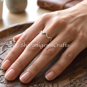 Könnte beinhalten: Ein Set aus drei Keramikbechern mit gesprenkelter, matter Oberfläche. Die Becher sind in Creme-, Hellgrau- und Dunkelgrautönen gehalten. Jeder Becher hat ein schlichtes, minimalistisches Design.