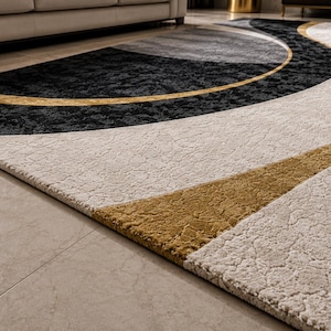 May include: A modern area rug with a geometric design. The rug features a combination of black, gray, beige, and gold colors. The design includes curved and angular shapes, creating a contemporary look. The rug is placed on a tiled floor.