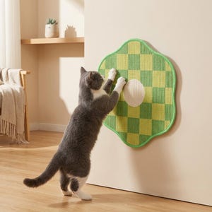 May include: A wall-mounted cat scratching pad featuring a green and yellow checkered pattern in a flower-like shape with a central white circle. The textured surface is designed for feline claw maintenance and is mounted on a flat vertical surface.