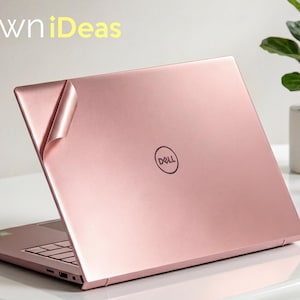 May include: A rose gold laptop skin applied to the lid of a Dell laptop, with a corner of the adhesive film partially peeled back. The text OwniDeas is visible in the upper left corner. The laptop has a metallic finish and a centred logo.