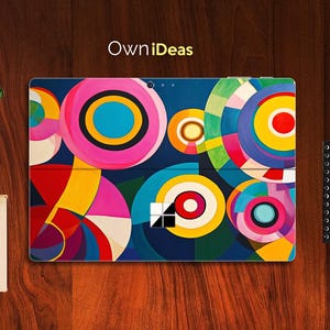 Puede incluir: Un diseño abstracto colorido con círculos y formas geométricas en tonos de rosa, amarillo, azul, rojo y blanco. El diseño está sobre un fondo azul oscuro y presenta el logotipo de Microsoft en el centro.