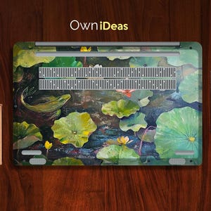 Puede incluir: Una piel para port&aacute;til con un dise&ntilde;o floral colorido que presenta nen&uacute;fares, flores de loto y un pez nadando por el agua. El dise&ntilde;o est&aacute; pintado en tonos de verde, azul y amarillo. La piel tiene el texto "OwnIdeas" impreso en ella.