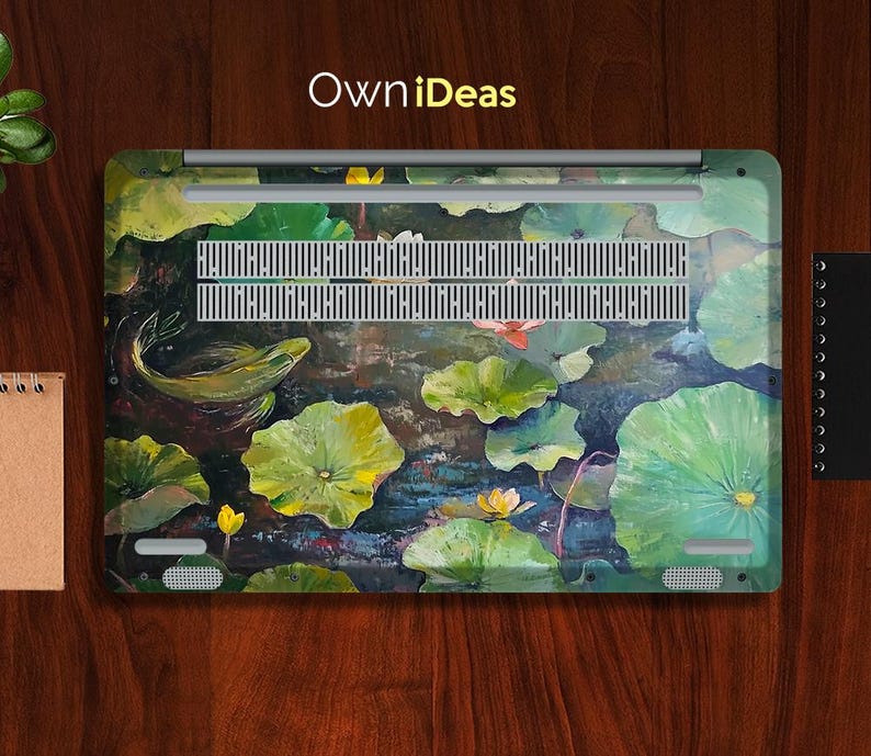 Puede incluir: Una piel para port&aacute;til con un dise&ntilde;o floral colorido que presenta nen&uacute;fares, flores de loto y un pez nadando por el agua. El dise&ntilde;o est&aacute; pintado en tonos de verde, azul y amarillo. La piel tiene el texto "OwnIdeas" impreso en ella.