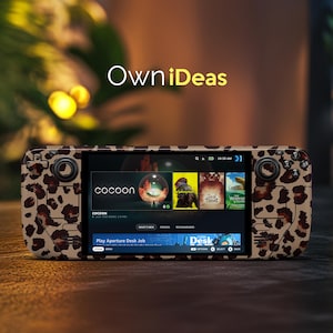 May include: A handheld gaming device with a leopard print case. The screen displays a game selection menu with the word "cocoon" visible. The device has buttons and joysticks on either side. The text "OwniDeas" is in the background.