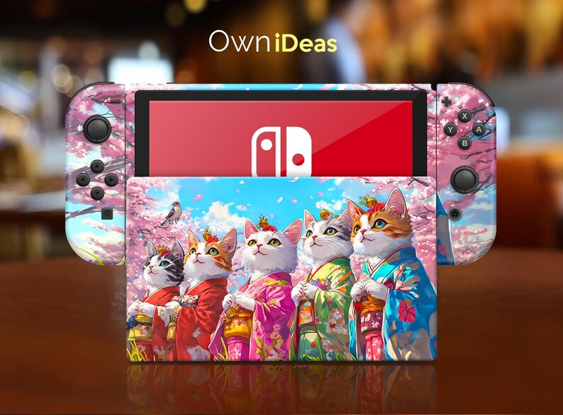 May include: A pink and white Nintendo Switch case with a floral design and a picture of five cats wearing kimonos. The case has the text "OwnIdeas" on the top.