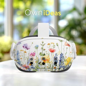 以下が含まれることがあります： 色とりどりの野草が描かれた、白いVRヘッドセット。 ヘッドセットにはグレーのストラップと、黄色の「OwniDeas」の文字が入っています。 ヘッドセットには3つの黒いセンサーが付いています。