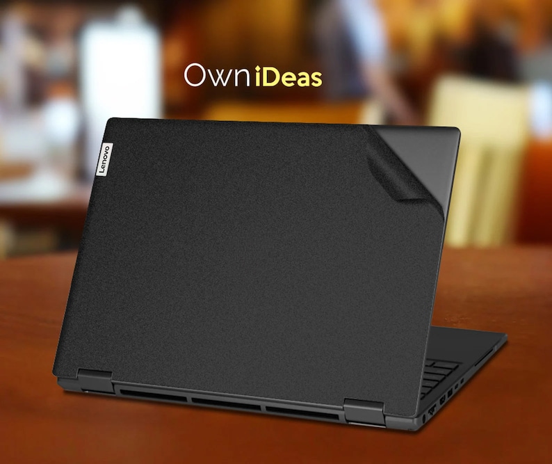 May include: A black laptop computer with the Lenovo logo on the lid. The laptop is closed and has a black screen protector on the lid. The laptop is sitting on a wooden table. The text "OwnIdeas" is written in yellow letters above the laptop.