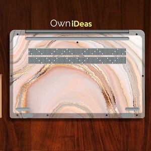 Op de afbeelding: Een laptop-skin met een roze, wit en gouden agaatpatroon. De skin heeft een uitsparing voor het ventilatiesysteem van de laptop. De tekst "OwnIdeas" is op de skin gedrukt.