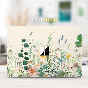 Puede incluir: Una piel para portátil con un diseño floral que presenta una variedad de flores y vegetación sobre un fondo crema. La piel tiene un recorte para la cámara del portátil y una pequeña ventana para el logotipo del portátil. El texto "OwnIdeas" está impreso en la piel.
